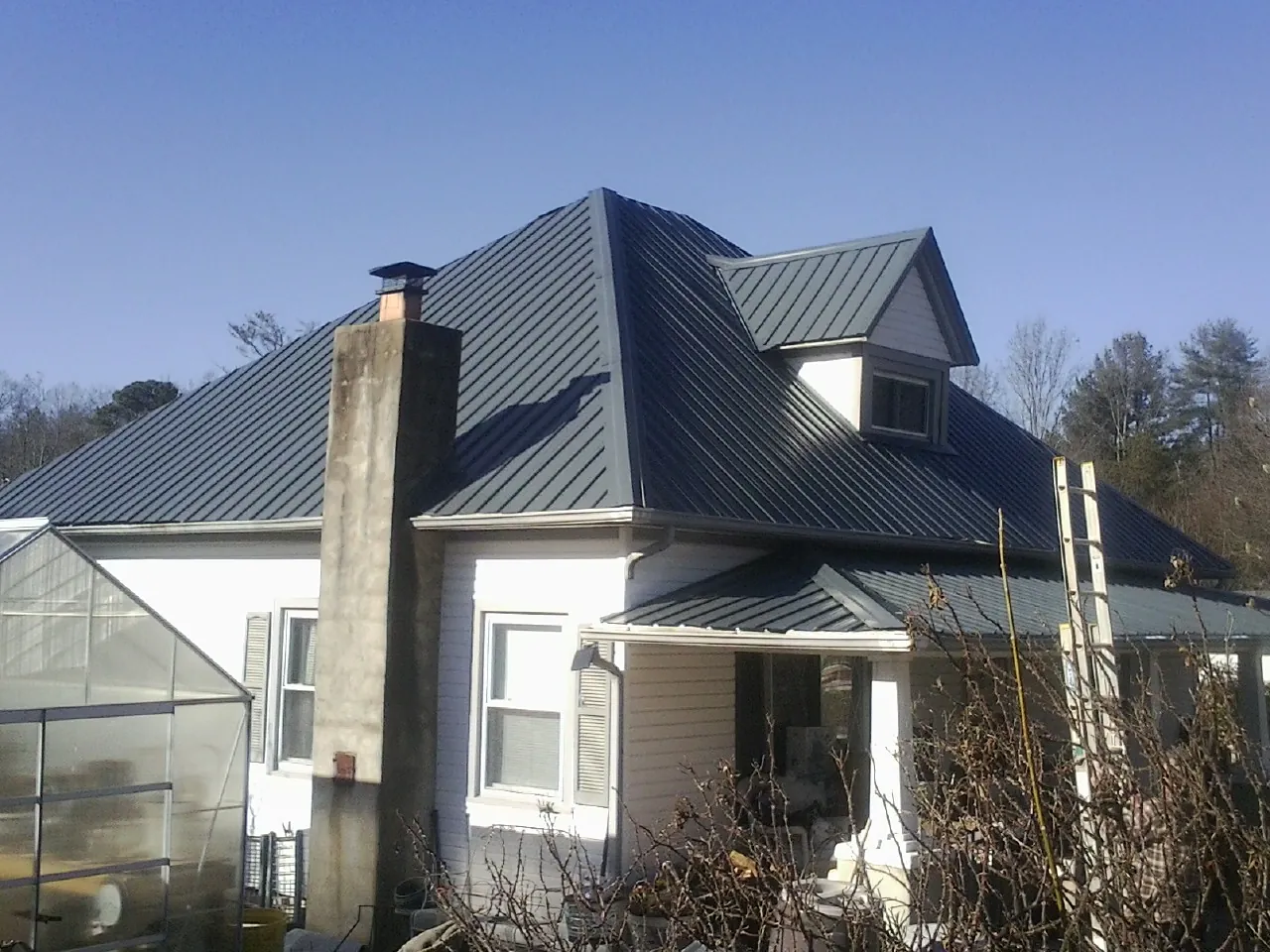 Dark blue standing seam metal roof on a white farmhouse with dormer — Slate & Tile Roof Repair by Roofing Brothers in Fishersville