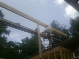 Carpenter setting a ridge beam over a new addition frame — Ice Dam Removal by Roofing Brothers in Fishersville