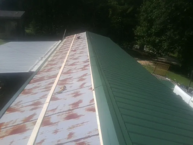 Old rusted panels beside newly installed green metal roofing — Wind Damage Roof Repair by Roofing Brothers in Fishersville