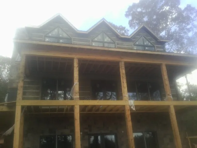 Dormers and porch framing on a large log home under construction — Roof Coating work by our crew in Fishersville
