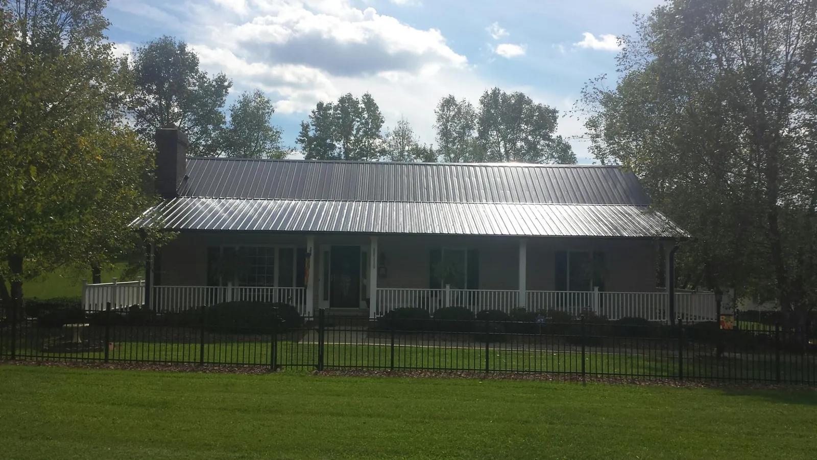 Gray metal roof on a brick ranch with a full width front porch — Gutter Guard Installation work by our crew in Fishersville
