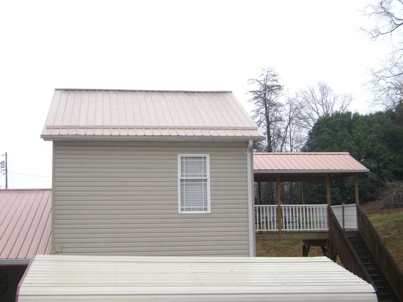 Tan metal roofs on a two story addition and attached porch, from a Roof Replacement job in Fishersville