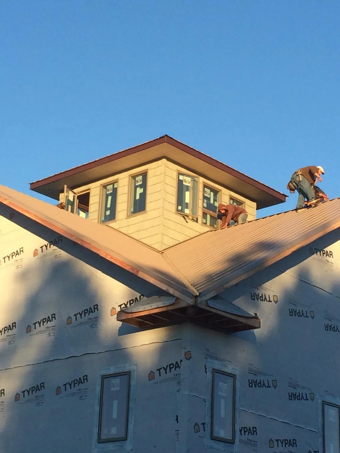 Roofers working around a rooftop cupola on a new metal roof at sunset — Roof Waterproofing in Fishersville by Roofing Brothers